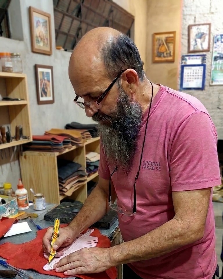 Artesão da Cia do Couro cortando o couro à mão no ateliê